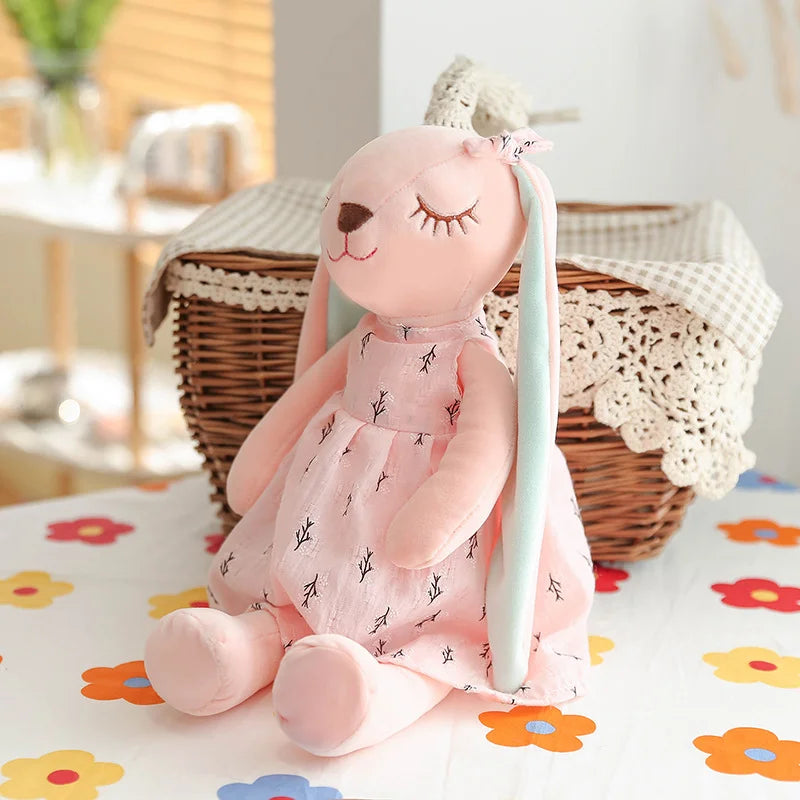淡いピンクの小枝柄ワンピースを着た眠り目のうさぎぬいぐるみ