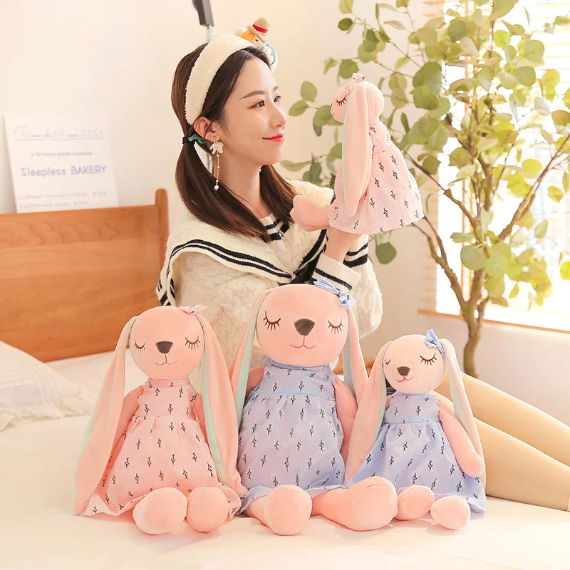 淡いピンクの小枝柄ワンピースを着た眠り目のうさぎぬいぐるみ